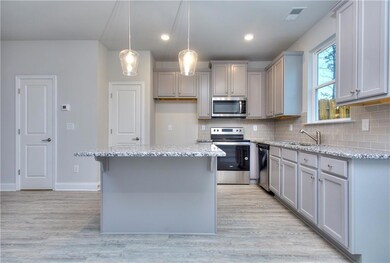 Kitchen with appliances with stainless steel finishes, gray cabinetry, light wood-style floors, tasteful backsplash, and recessed lighting