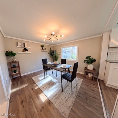 Dining space featuring dark wood-type flooring, a chandelier, and ornamental molding