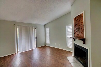 Unfurnished living room with vaulted ceiling, a textured ceiling, plenty of natural light, a fireplace with flush hearth, and dark wood-style flooring