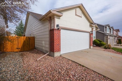 View of property exterior featuring a garage, brick siding, driveway, and fence