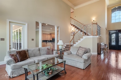 Living room with a high ceiling, ornamental molding, dark hardwood / wood-style floors, and decorative columns