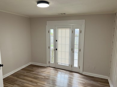 Entryway with wood finished floors, baseboards, and crown molding