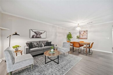 Living area featuring wood finished floors, baseboards, ornamental molding, and a chandelier