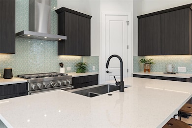 Kitchen featuring a sink, gas range, wall chimney