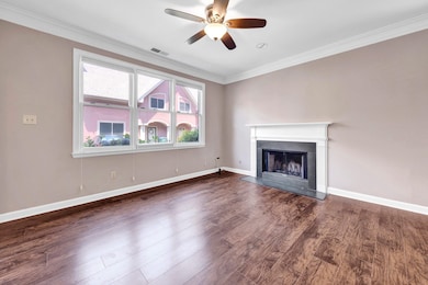 Unfurnished living room with ornamental molding, a fireplace, a ceiling fan, and wood finished floors