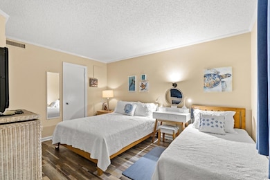 Bedroom featuring dark wood finished floors, crown molding, and a textured ceiling