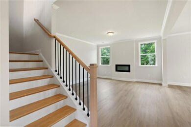 Stairway featuring wood finished floors, a glass covered fireplace, baseboards, and crown molding