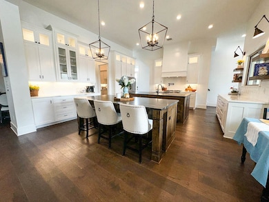 Kitchen featuring a large island with sink, recessed lighting, a chandelier, and dark wood finished floors