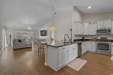 Kitchen with stainless steel appliances, dark countertops, open floor plan, a peninsula, and white cabinetry