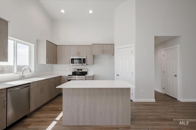 Kitchen featuring a towering ceiling, stainless steel appliances, modern cabinets, light wood finished floors, and a kitchen island