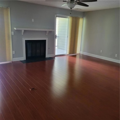 Elegant living room with dark wood-type flooring, a fireplace with flush hearth, a ceiling fan, and a textured ceiling