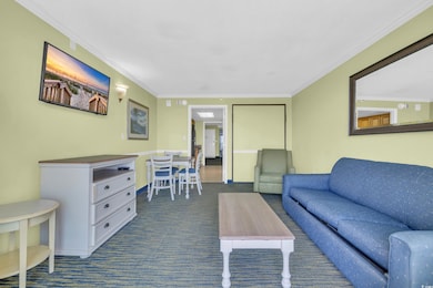 Living area with dark colored carpet and crown mol