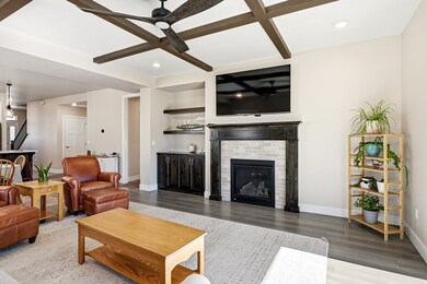 Living room featuring coffered ceiling, beam ceiling, a fireplace, ceiling fan, and light wood-style floors