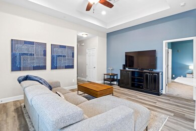 Living room with ceiling fan, baseboards, wood fi