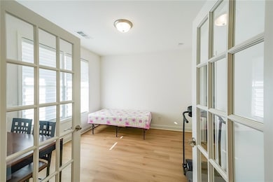 Bedroom with french doors, visible vents, light wo