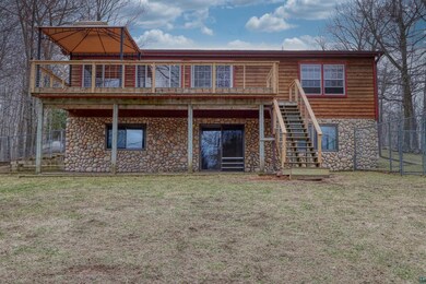 Rear view of house featuring fence, stairway, a yard, and stone siding