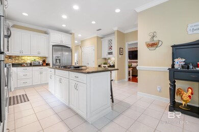 Kitchen featuring appliances with stainless steel finishes, tasteful backsplash, a center island, ornamental molding, and white cabinetry