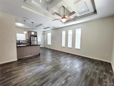 Unfurnished living room with dark wood-style floors, a sink, a raised ceiling, and baseboards