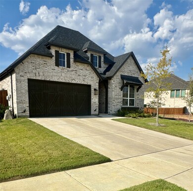 French country inspired facade featuring brick siding, driveway, and roof with shingles