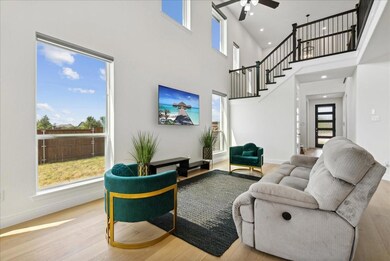 Living room with stairway, baseboards, ceiling fan, and wood finished floors