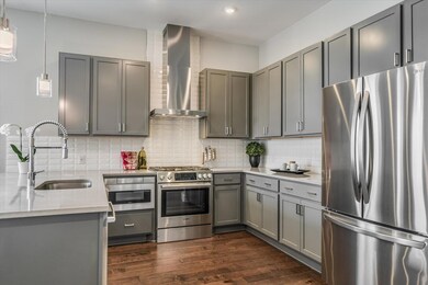 Kitchen with a sink, gray cabinetry, wall chimney