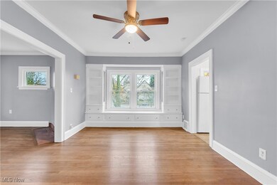 Spare room featuring crown molding, plenty of natural light, and light hardwood / wood-style floors