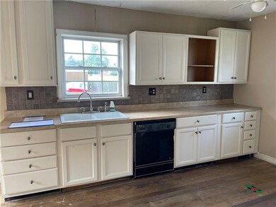 Kitchen with dark hardwood flooring, black dishwas