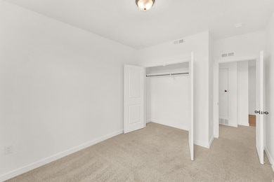 Unfurnished bedroom with light carpet and a closet