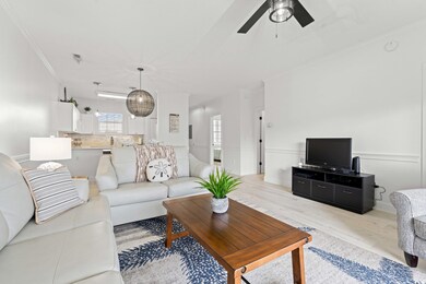 Living room with ornamental molding, wood finished floors, and a ceiling fan
