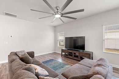 Living area featuring baseboards, a ceiling fan, w