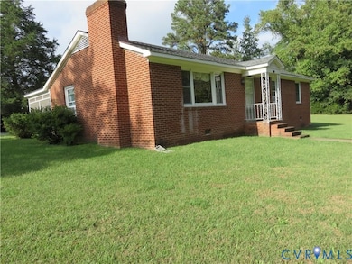 View of side of property featuring a lawn, brick siding, a chimney, and crawl space