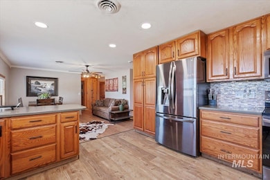 Kitchen featuring stainless steel appliances, light wood-type flooring, tasteful backsplash, crown molding, and ceiling fan