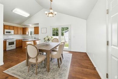 Dining area featuring a chandelier, high vaulted ceiling, and dark wood finished floors. AI generated photo