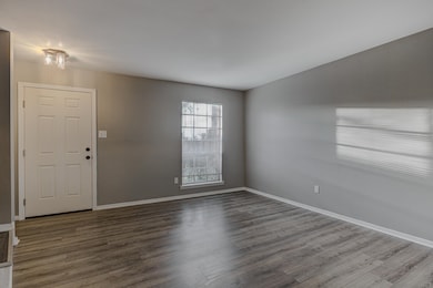 Unfurnished room featuring baseboards and dark woo