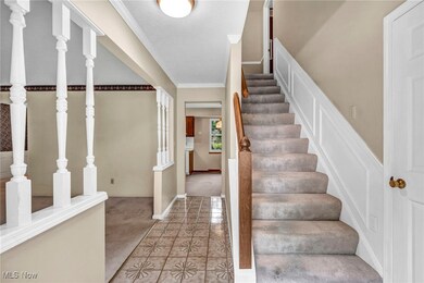Stairs with crown molding, light tile patterned floors, and a textured ceiling