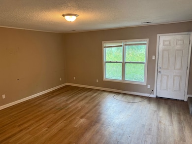 Spare room featuring a textured ceiling, wood finished floors, and crown molding