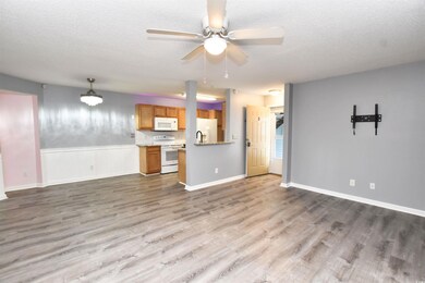 Unfurnished living room with a textured ceiling, a ceiling fan, and light wood-style flooring