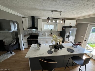 Kitchen featuring white cabinets, hardwood / wood-style flooring, appliances with stainless steel finishes, and wall chimney range hood