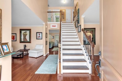 Stairway with wood finished floors, ornamental molding, and baseboards