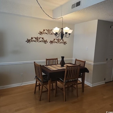 Dining space with a textured ceiling, light wood-style flooring, and a chandelier