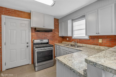 Kitchen with white cabinetry, sink, and stainless 