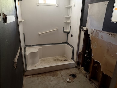 Bathroom featuring light tile patterned flooring and a stall shower