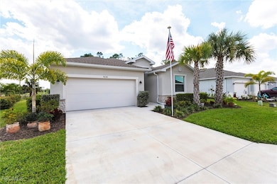 Single story home with a garage, driveway, stucco siding, stone siding, and a front yard