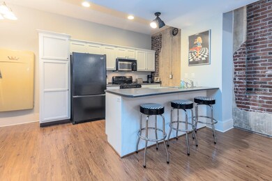 Kitchen featuring black appliances, a kitchen bar, dark countertops, and light wood-style floors