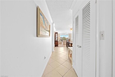 Hallway with baseboards, a textured ceiling, light tile patterned floors, and crown molding