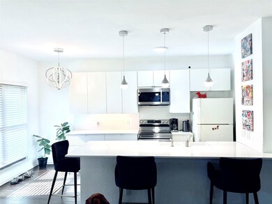 Kitchen featuring white cabinetry, a kitchen breakfast bar, stainless steel appliances, and hanging light fixtures