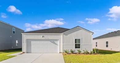 View of front of property with board and batten siding, a front yard, concrete driveway, and an attached garage