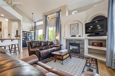 Living area with wood finished floors, a fireplace, a towering ceiling, and built in shelves