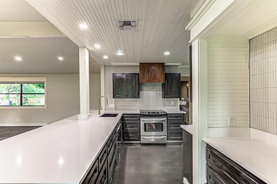 Kitchen with electric range, a peninsula, a sink,