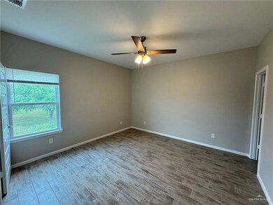 Empty room featuring wood finished floors, a ceiling fan, and baseboards